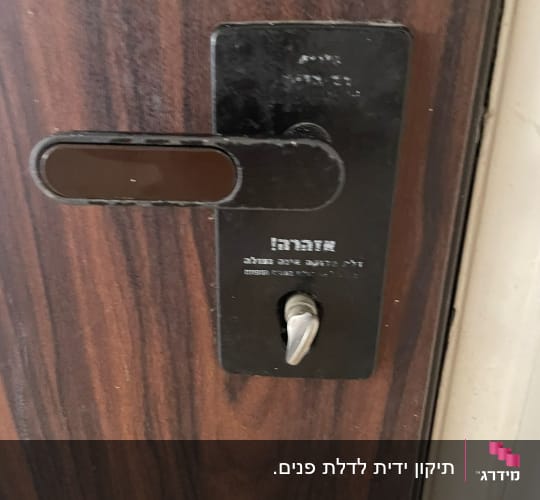 מנעול דלת עם ידית מתכת על רקע עץ